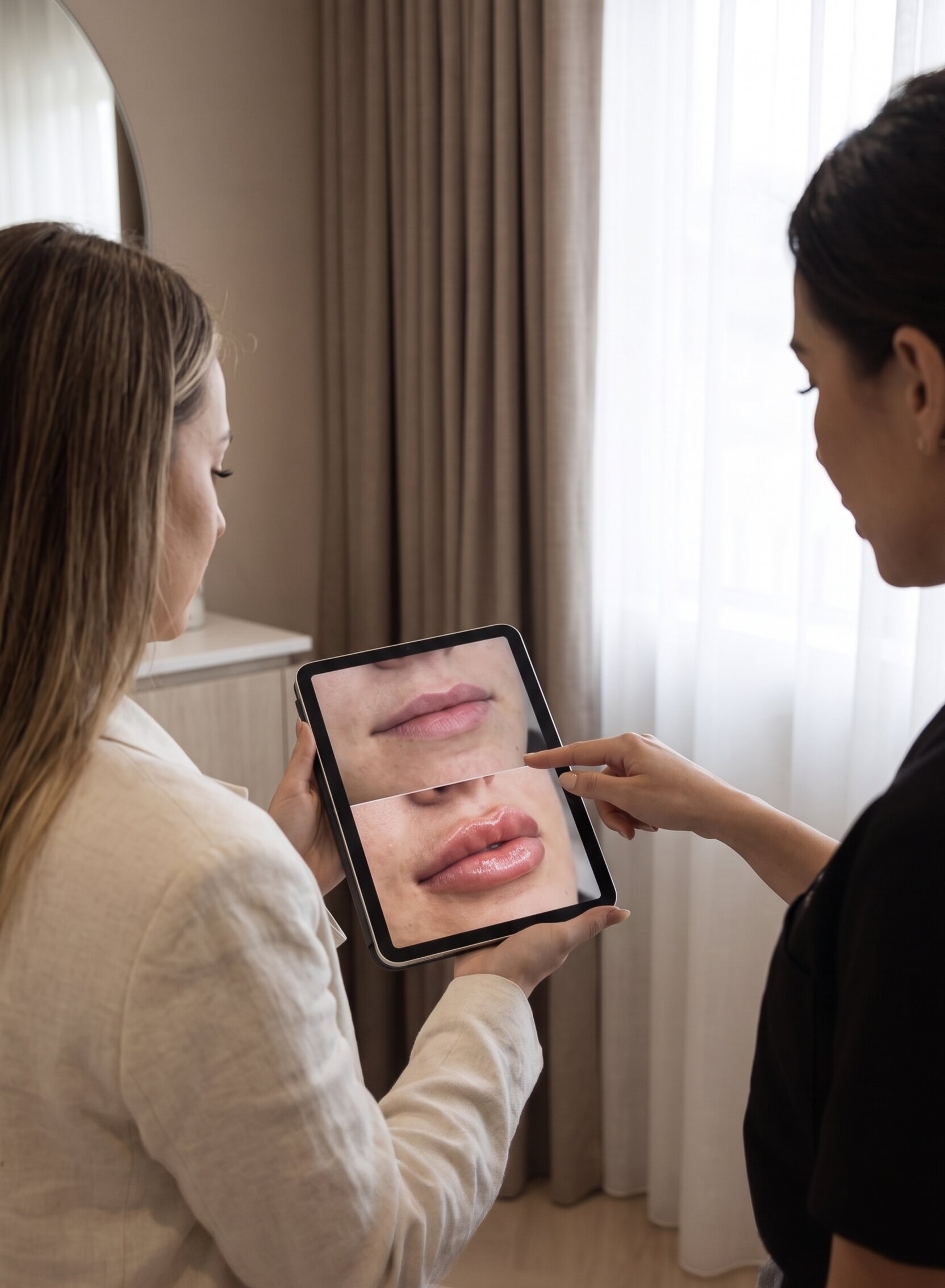 Provider and client reviewing lip enhancement before/after on a tablet during a consultation